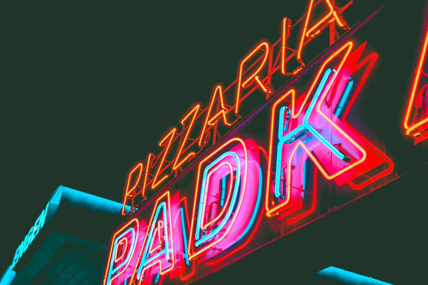 Neonschild der Pizzeria Park leuchtet an einer Außenwand.